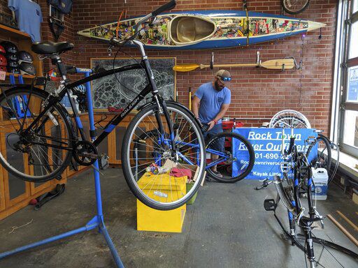 Samuel Ellis inspects a bike at his kayak and bicycle tour and rental company